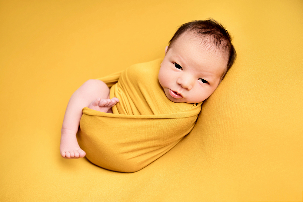 Baby boy wrapped in a yellow blanket taken by Alice James Photography, newborn photographer Hertfordshire