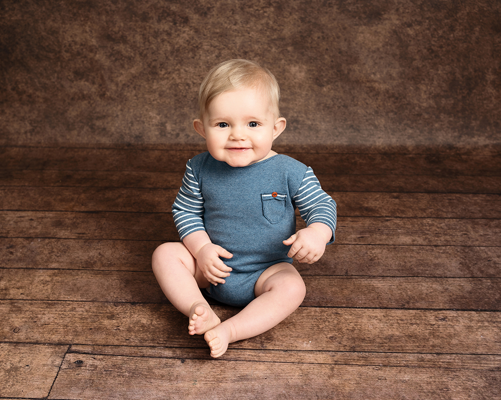 A baby boy smiling at the camera taken by Alice James Photography, baby photographer Hitchin