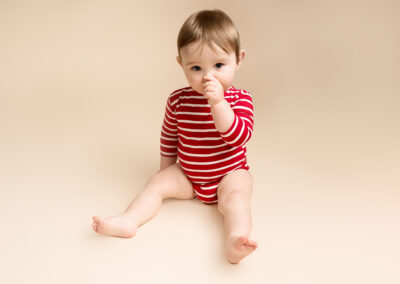 Baby boy wearing a red striped onesie. Taken at his baby photoshoot Hitchin