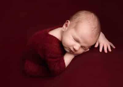 Baby boy wearing red taken by Alice James Photography, newborn Photographer Hertfordshire