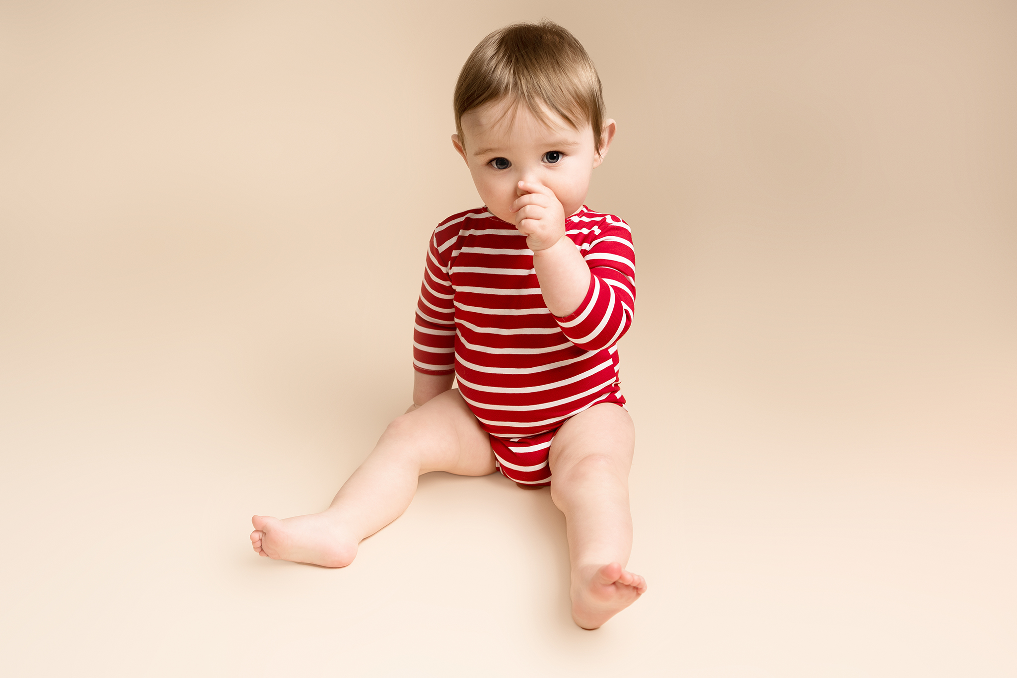 Baby boy wearing a red and white striped bodysuit taken by Alice James Photography, newborn photographer Hitchin