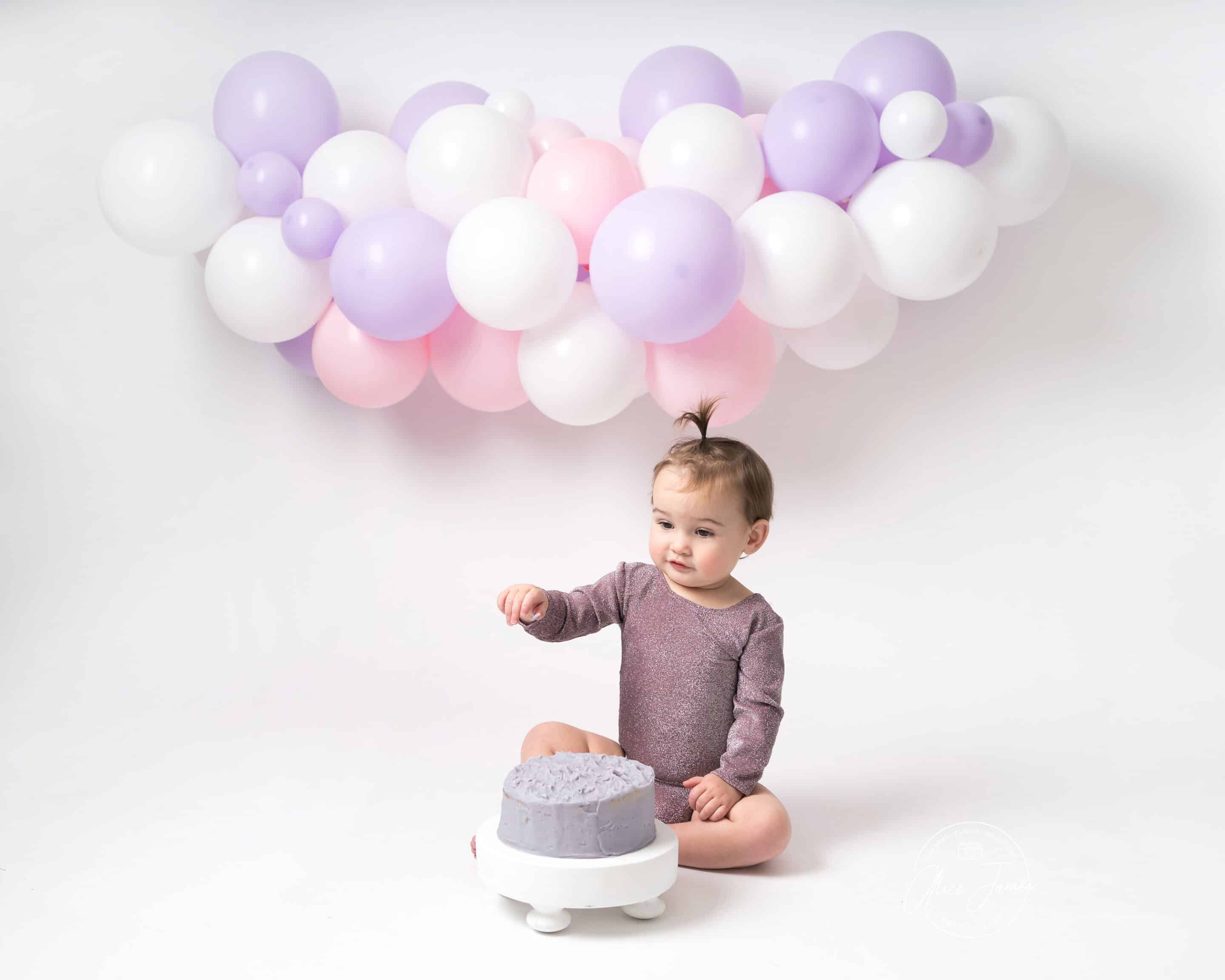 Baby girl in front of balloon wall taken at a cake smash photoshoot in Hitchin.